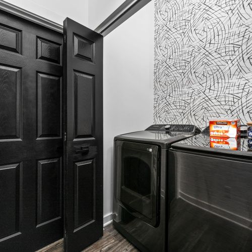 Sleek laundry vibes—black machines, bold wallpaper, and detergent ready to roll.