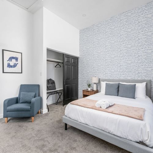 Blue vibes all around—cozy chair, playful art, and smart touches to make you feel at home.