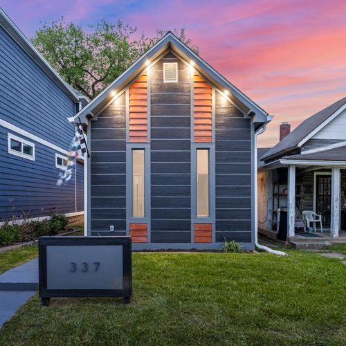 Modern vibes from the curb — dark siding, wood accents, and a bold house number that makes a statement, can’t forget our Indianapolis Motor Speedway flag!