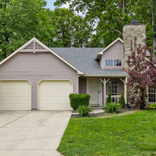Tucked under a canopy of trees, this cozy home features a two-car garage, stone chimney, and a warm, welcoming vibe from the moment you arrive.