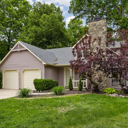 Tucked under a canopy of trees, this cozy home features a two-car garage, stone chimney, and a warm, welcoming vibe from the moment you arrive.