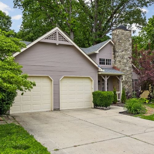 Tucked under a canopy of trees, this cozy home features a two-car garage, stone chimney, and a warm, welcoming vibe from the moment you arrive.