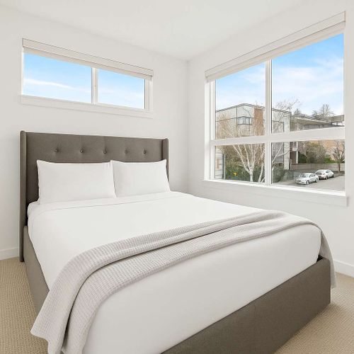 Bright second bedroom with a queen bed and soft carpet. Comfortable and quiet.