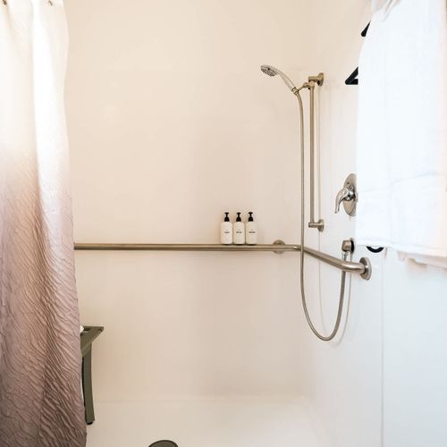 ADA-accessible shower with roll-in capability, grab bars, and shower bench