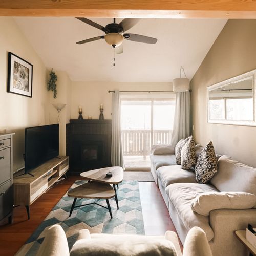 Living area with electric fireplace, flatscreen TV, reclining seats, and balcony access