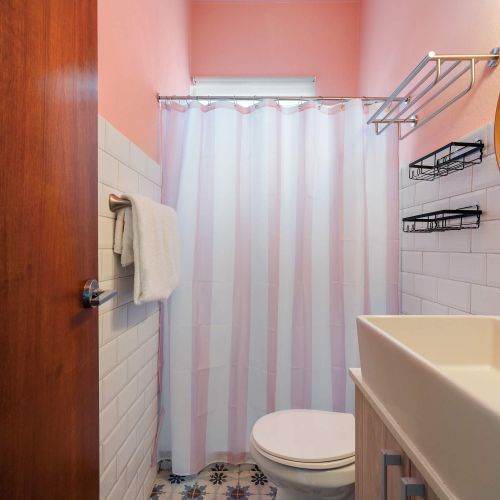 modern bathroom with large mirror, shower curtains, towels, white sink with stainless steel faucet, WC