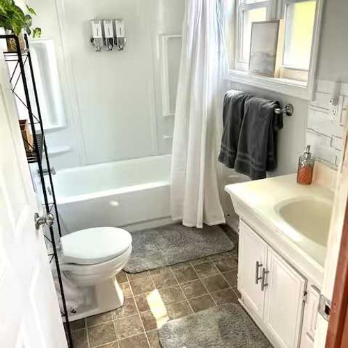 Full bathroom on the main level, featuring a vanity and a shower tub combo.