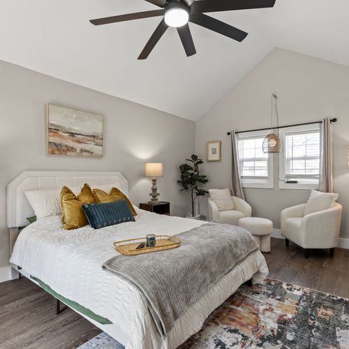Beautiful primary bedroom with a cozy seating area, stunning light fixtures, and the perfect natural light.