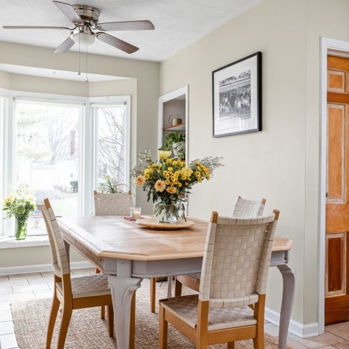 Sun-drenched dining area with large bay windows overlooking the neighborhood — a beautiful spot for shared meals.