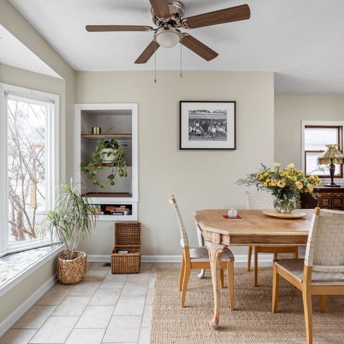 Sun-drenched dining area with large bay windows overlooking the neighborhood — a beautiful spot for shared meals.