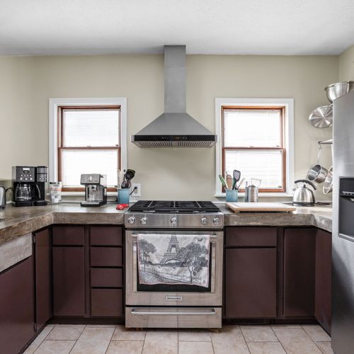 Fully equipped chef's kitchen with stainless steel appliances, gas range, and custom concrete countertops.