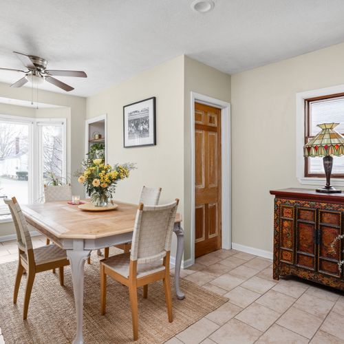 Sun-drenched dining area with large bay windows overlooking the neighborhood — a beautiful spot for shared meals.