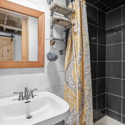 Bonus basement bathroom featuring a sleek tiled shower and industrial-inspired finishes. The basements is mainly unfinished!