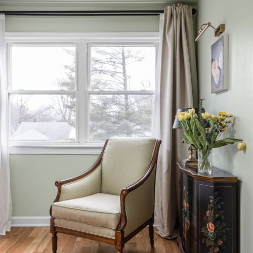 Charming reading corner in the primary suite with a comfy chair and fresh blooms — perfect for unwinding.
