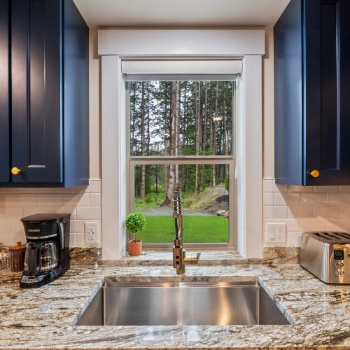 Do the dishes with a view—bright, airy sink space facing lush outdoor scenery.