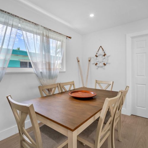 This bright dining space features a spacious table ideal for both shared meals and a comfortable remote work setup.