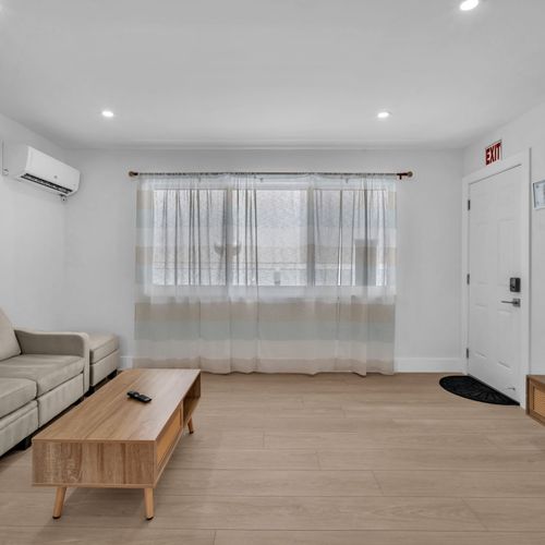 Simple yet cozy living area featuring a comfy sofa, airy natural light, and a dining space, perfect for relaxing after a day at the beach or a calm night in.