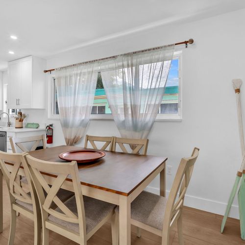 This bright dining space features a spacious table ideal for both shared meals and a comfortable remote work setup.