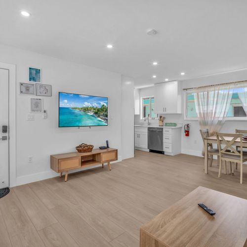 Simple yet cozy living area featuring a comfy sofa, airy natural light, and a dining space, perfect for relaxing after a day at the beach or a calm night in.