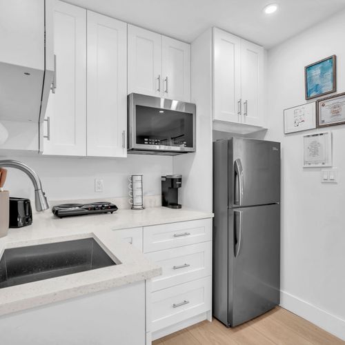 Clean and practical kitchenette featuring a fridge, electric cooktop, microwave, Keurig, and ample storage for your stay.