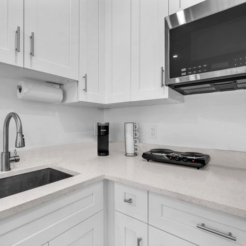 Compact kitchenette with a refrigerator, two-burner electric stove, microwave, Keurig, and ample cabinet storage for short or long stays.