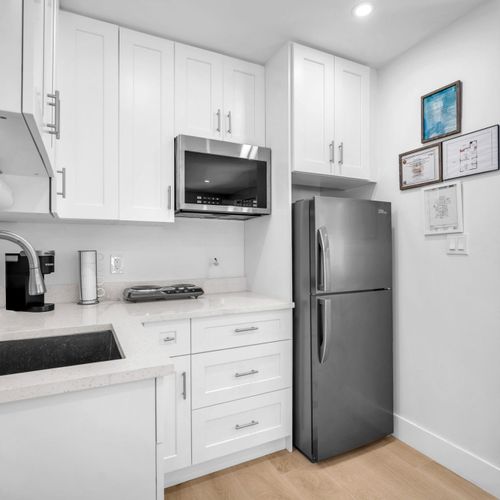 Compact kitchenette with a refrigerator, two-burner electric stove, microwave, Keurig, and ample cabinet storage for short or long stays.