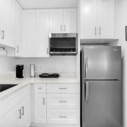 Compact kitchenette with a refrigerator, two-burner electric stove, microwave, Keurig, and ample cabinet storage for short or long stays.