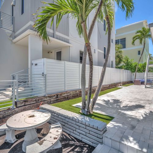 Enjoy a large open outdoor space with a backyard lounge area surrounded by tropical greenery.