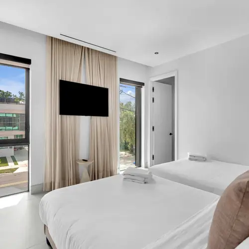 Featuring twin beds, modern minimalist art, and a large flat-screen TV, this room is the ultimate setup for guests or kids. Floor-to-ceiling windows keep the space bright, airy, and inviting.