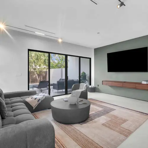 The living area features a super comfortable sectional sofa and a beautiful round coffee table, but the real highlight is the massive glass doors. Effortlessly connecting the inside space to the outdoors.