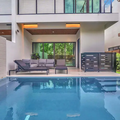 Experience seamless indoor-outdoor living in this masterfully designed modern backyard. The property boasts a luxury inground pool with crisp white architectural lines, flanked by a dedicated poolside lounge area.