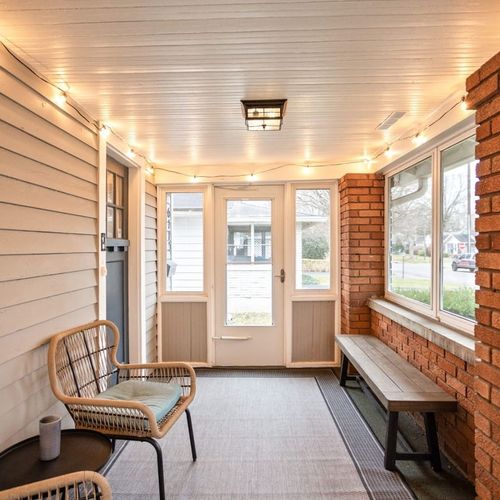 Sunlit Porch Retreat: Unwind in this charming, bright space adorned with cozy seating and twinkling lights!