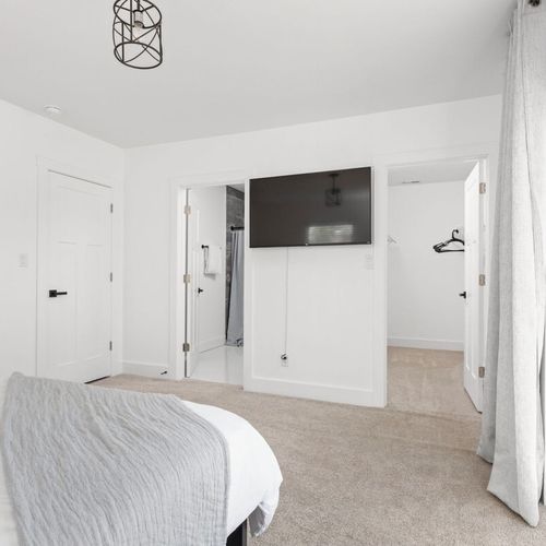 Primary Bedroom: Bright and airy retreat with a plush bed, modern TV, and breezy views!