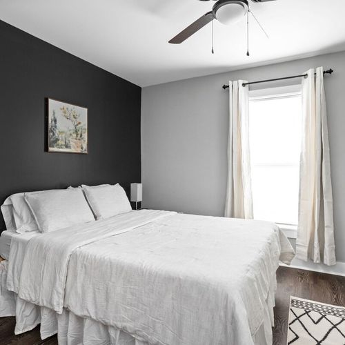 Another view of the 2nd bedroom with tv, queen bed, dresser, and closet.