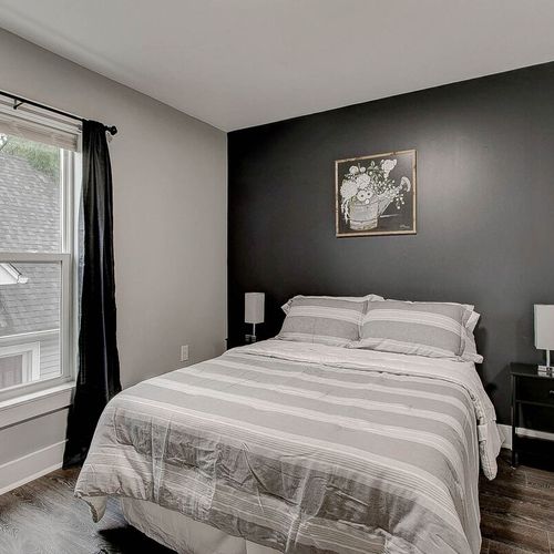 Second bedroom featuring a queen bed and TV, complemented by a stylish accent wall and tasteful decor.