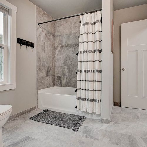 Tiled shower, stocked with shampoo, conditioner, and body wash