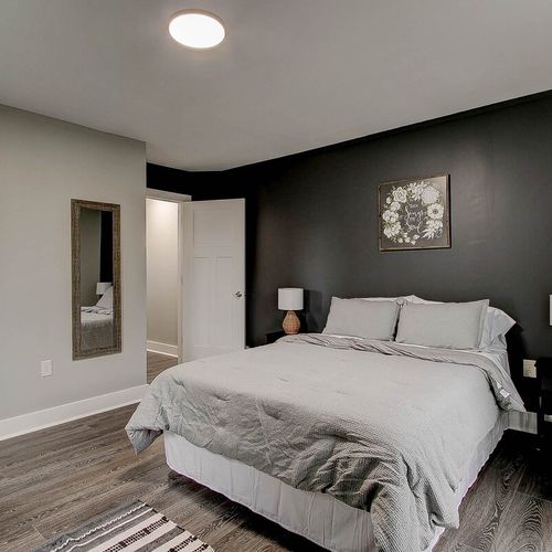 Cozy up in the main bedroom featuring a queen bed, closet, TV, additional seating, and a stylish accent wall.