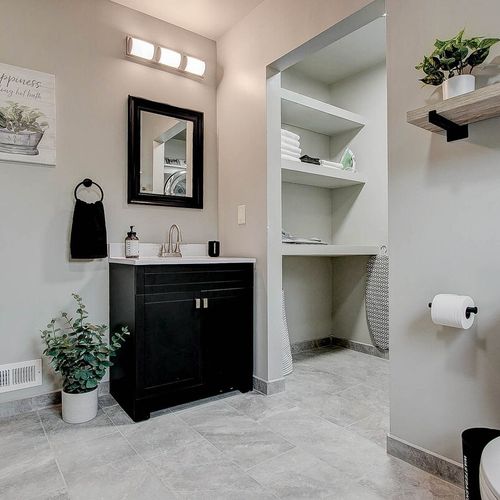 Fully stocked modern bathroom with a view of the laundry room with linens and ironing station.