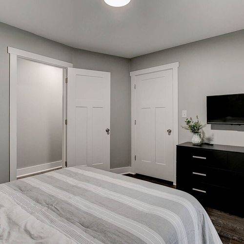 Another view of the cozy second bedroom, featuring a queen bed, TV, dresser, and closet—offering comfort, convenience, and a perfect spot to unwind after a day in the city.