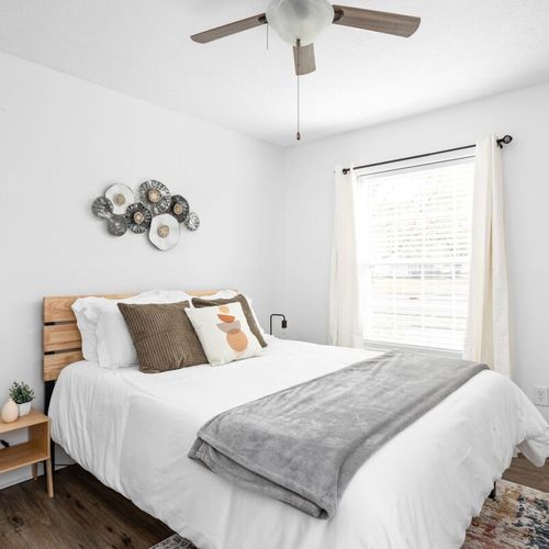 A welcoming bedroom adorned with an elegantly appointed queen bed and two windows, establishing a bright and inviting atmosphere.