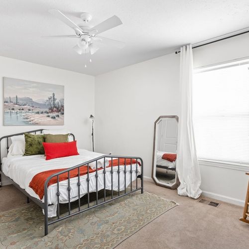 an inviting queen-sized comfortable bed, adorned with elegant frames on the wall. Additionally, there's extra cozy seating near the window for your relaxation and enjoyment.