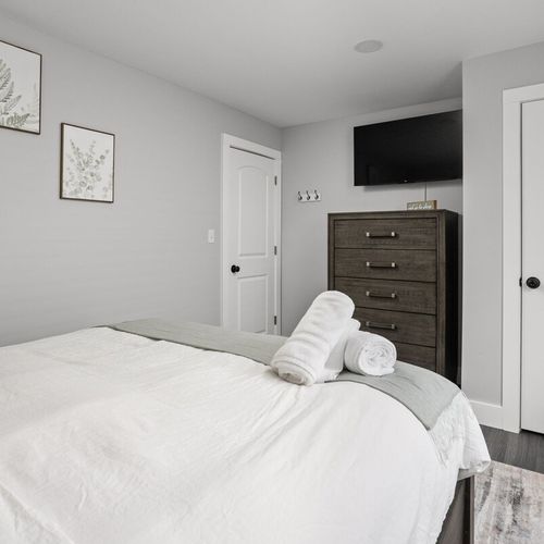 First Bedroom: Modern tranquility awaits with a plush queen bed, stylish decor, and a wall-mounted TV!
