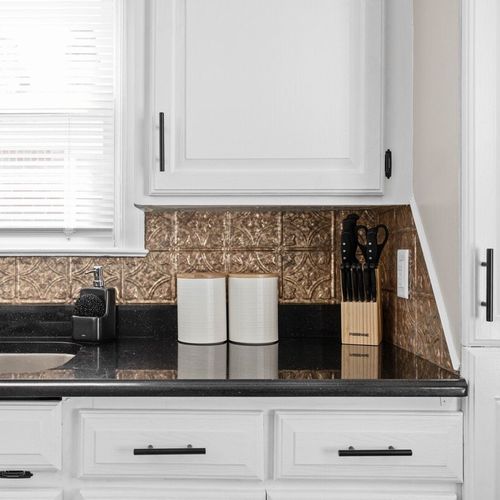 Adorable storage cabinets, well-stocked with kitchen utensils, and a gleaming kitchen sink and countertops, adding charm and functionality to the space.