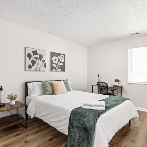 We've created a cozy space with a bed adorned in soft pillows and fresh linens. Bedside tables with lamps and a few frames on the wall enhance the ambiance, ensuring a restful sleep in our carefully designed bedroom.