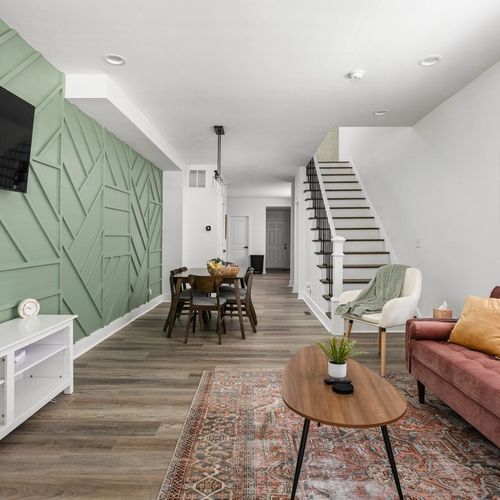 A captivating view of our inviting living area, featuring a glimpse of the elegant staircase and a welcoming dining table, creating a harmonious and stylish living space.