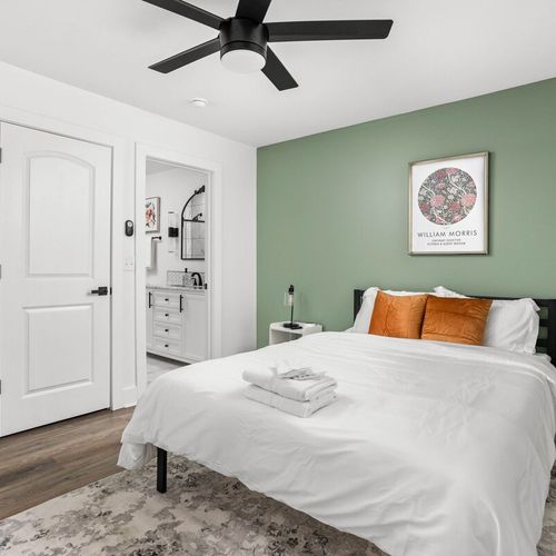 Ultimate comfort in our bedroom, boasting a very comfortable bed with plush pillows, bath towels, a bedside table with a lamp, and the convenience of an attached bathroom for a seamless retreat.