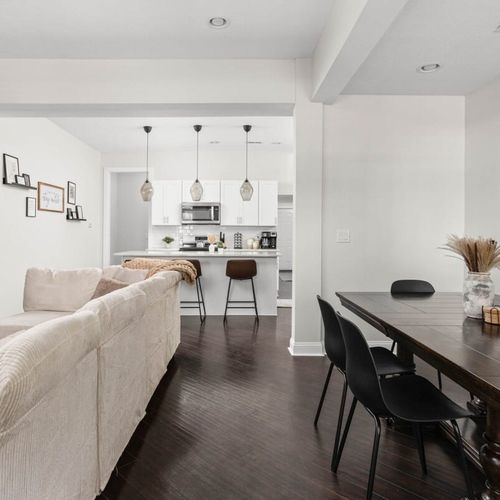 A view of the dining table, a sofa on the of the living area to the kitchen.