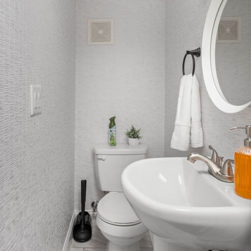 Discover our well-appointed toilet room, complete with fresh towels, hand soap, a sink, a mirror, and a delightful air freshener for your comfort.