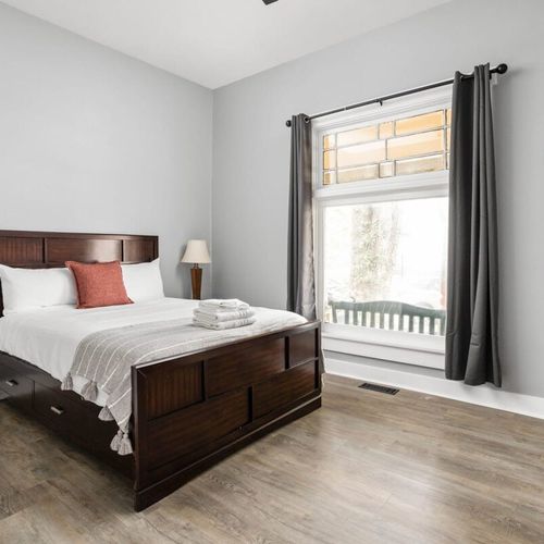 Spacious bedroom featuring a window that bathes the room in natural light. Enjoy the warmth of a bedside table and lamp.