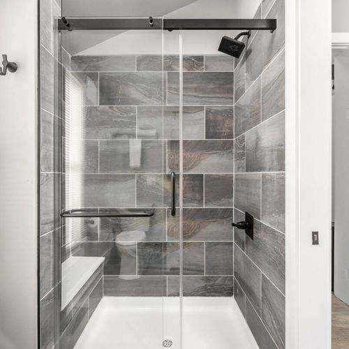 Elegantly tiled shower, accompanied by  shampoo, conditioner, and body wash. Wrap yourself in the comfort of fresh, laundered towels for a truly rejuvenating experience.